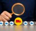 Magnifying glass focusing on a yellow truck icon among blue truck icons, symbolizing fleet tracking and logistics management.